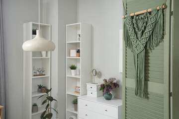 Interior of living room with green folding screen, drawers and shelf units