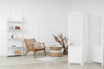 Interior of living room with white folding screen, armchair and shelf unit