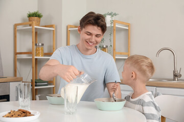 Happy father and his little son eating cornflakes with milk on breakfast at home