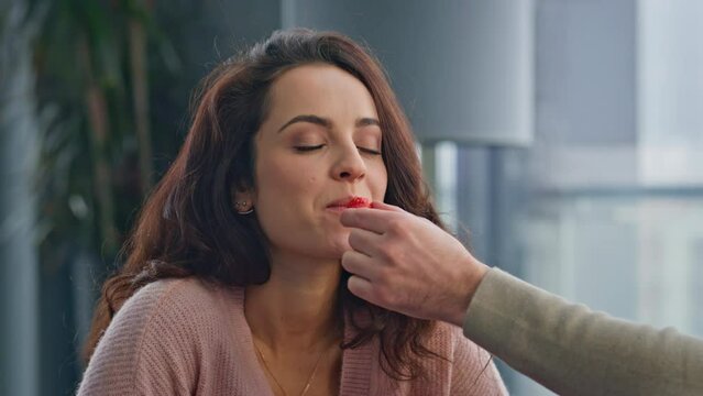Man giving strawberry woman feeding wife at breakfast closeup. Lady biting berry