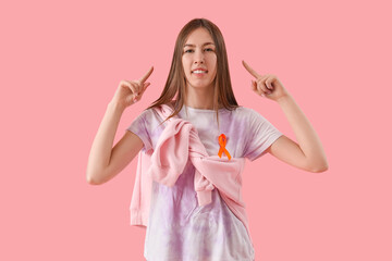 Beautiful young happy woman with ribbon pointing at head on pink background. Multiple Sclerosis...