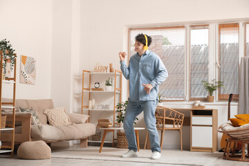 Dancing young man in headphones listening to music at home