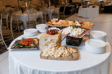 Cheeses on the table in the restaurant close-up. Large wheel of cheese cut into pieces, different cheeses, parmesan, mozzarella. A large assortment of cheese dishes. Snacks at weddings and holidays