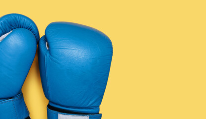 Blue boxing gloves isolated on yellow background close-up with free space for text. A pair of blue...