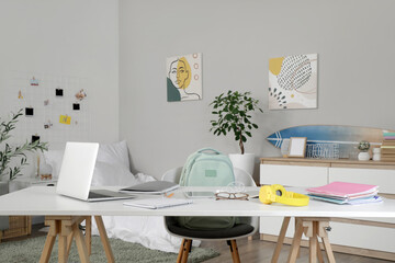 Student's table with laptop and copybooks in bedroom