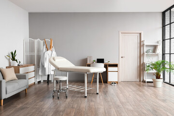 Interior of medical office with couch, sofa and doctor's workplace
