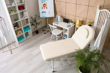 Interior of medical office with couch, folding screen and doctor's workplace