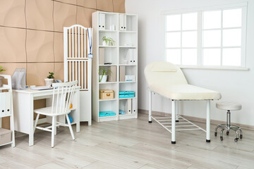 Interior of medical office with couch, doctor's workplace and shelf unit