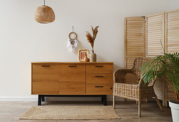 Interior of living room with wooden commode and armchair