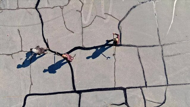 In course of worker patching patcher performs coated crack filling asphalt crack sealing bitumen emulsion road surface restoration