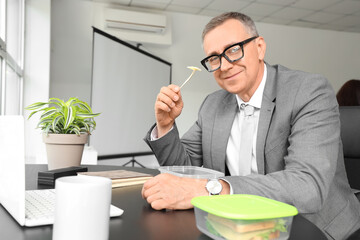 Mature businessman having lunch in office