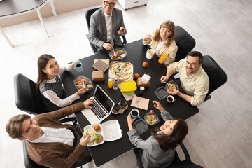 Group of business people having lunch at table in office, top view