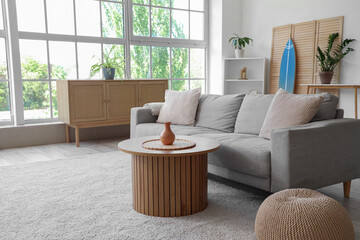 Interior of living room with sofa, table and surfboard