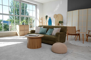 Interior of stylish living room with sofa, table and surfboard