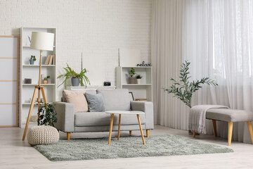 Interior of stylish living room with folding screen, grey sofa, shelving unit and coffee table
