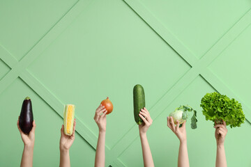 Female hands holding fresh vegetables on green background