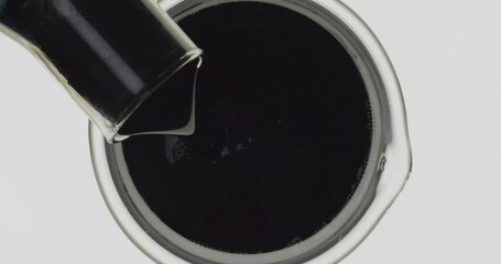 Scientist chemist pouring used engine oil from glass into beaker., Top view

