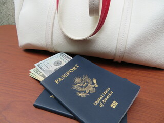 American passport and money on table with white tote bag