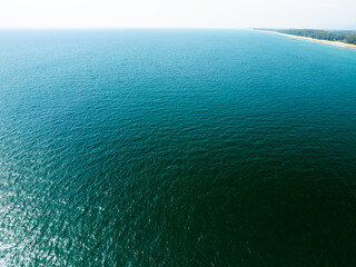 Fototapeta premium Aerial view of a blue sea surface water texture background,Sun reflections over ocean, Aerial flying drone view Waves water surface texture on sunny tropical ocean in Phuket island Thailand
