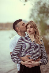 Obraz premium Couple standing by the river, man hugging woman.