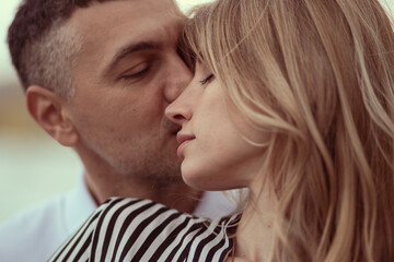 Man kissing woman on the head, hugging her from behind.