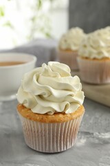 Tasty cupcake with vanilla cream on grey table, closeup