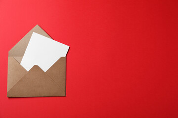 Letter envelope with card on red background, top view. Space for text