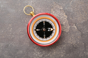 One compass on grey textured background, top view