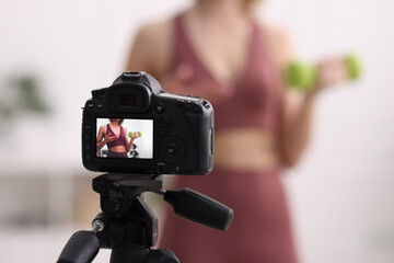 Sports blogger with dumbbell recording fitness lesson at home, focus on camera. Space for text