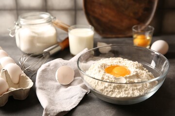 Making dough. Flour with egg yolk in bowl on grey table, closeup