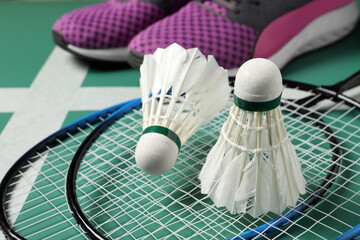 Feather badminton shuttlecocks, rackets and sneakers on court, closeup