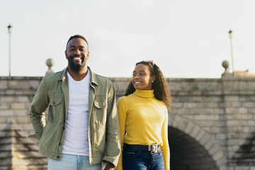smiling african american couple portrait in front of a bridge