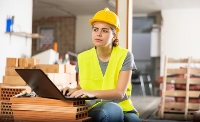Portrait of young woman architect with laptop working on indoor building construction site