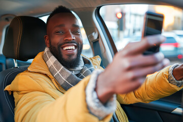 Young african american man in a car taking a selfie with her phone.