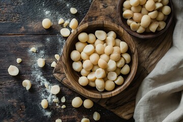 Raw peeled macadamia nuts in wooden bowl on rustic wooden background