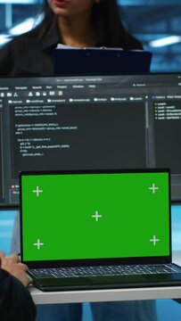 Vertical video Manager in server hub supervising engineers looking for misconfiguration using isolated screen device. Woman coordinating experts mending data center bugs with mockup notebook, close up