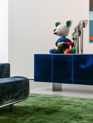 In one corner of the gallery stands a colorful sideboard with a sculpture of stacked stuffed teddy bears in different colors, a beige green patterned carpet covers the floor, and blue velvet sofas lea