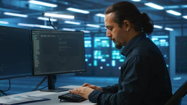 System administrator working in high tech server room capable of storing vast amounts of data, using computer. IT engineer typing on PC keyboard, upgrading servers controlling network resources