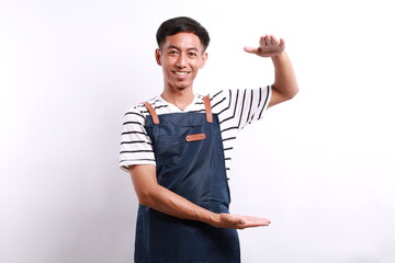 Smiling handsome asian barista showing something long or large, standing over white background