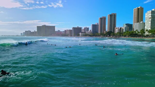 Aerial drone shot flying low over ocean and waves at Waikiki Beach as surfers ride the waves