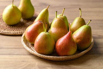 Fresh pear fruit in natural basket on wooden background
