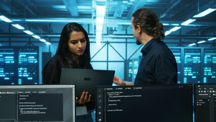 Technicians working in high tech server hub, analyzing data on laptop to ensure seamless data flow. Coworkers examining equipment in data center, ensuring system integrity and security