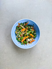 A blue bowl brimming with sautéed green beans, carrots, and eggs invites you to indulge in a colorful, nutritious feast. The vibrant vegetables blend harmoniously with the fluffy, golden eggs.