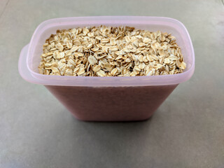 A top-down photo captures the wholesome allure of oats stored in a transparent, pink, oval-shaped jar.