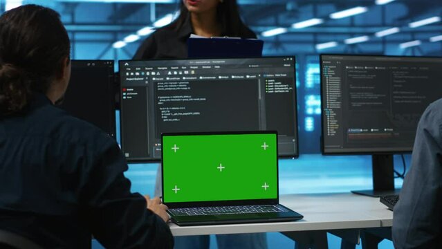 Manager in server hub supervising engineers looking for misconfiguration using isolated screen device. Woman coordinating experts mending data center bugs with mockup notebook, close up panning shot