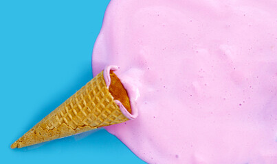 Melting ice cream with waffle cone on blue background.