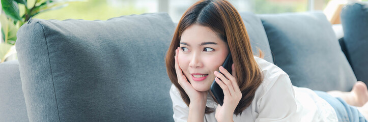 Banner Women sitting on sofa using smartphone, credit card to shopping online with smiling face shopaholics. Panorama Happy asian women lay down use smartphone. Woman online shopping with copy space - Powered by Adobe