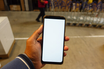business owner holding phone mock up in warehouse.