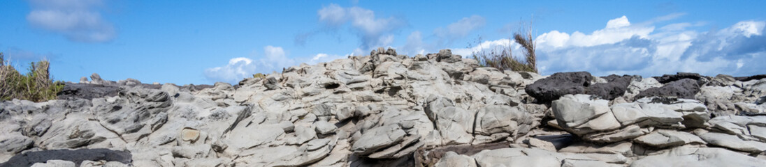 Weathered light gray lava rock landscape leading up to a sunny blue sky, Makalua-Puna Point, Maui, Hawaii, as a nature background
