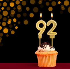 Number 92 birthday candle - Cupcake on black background with out of focus lights